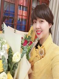 A person holding flowers and smiling

Description automatically generated